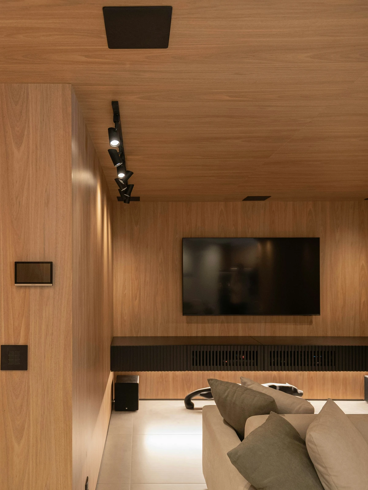 A modern wood-paneled media room with integrated display, speakers, and architectural lighting