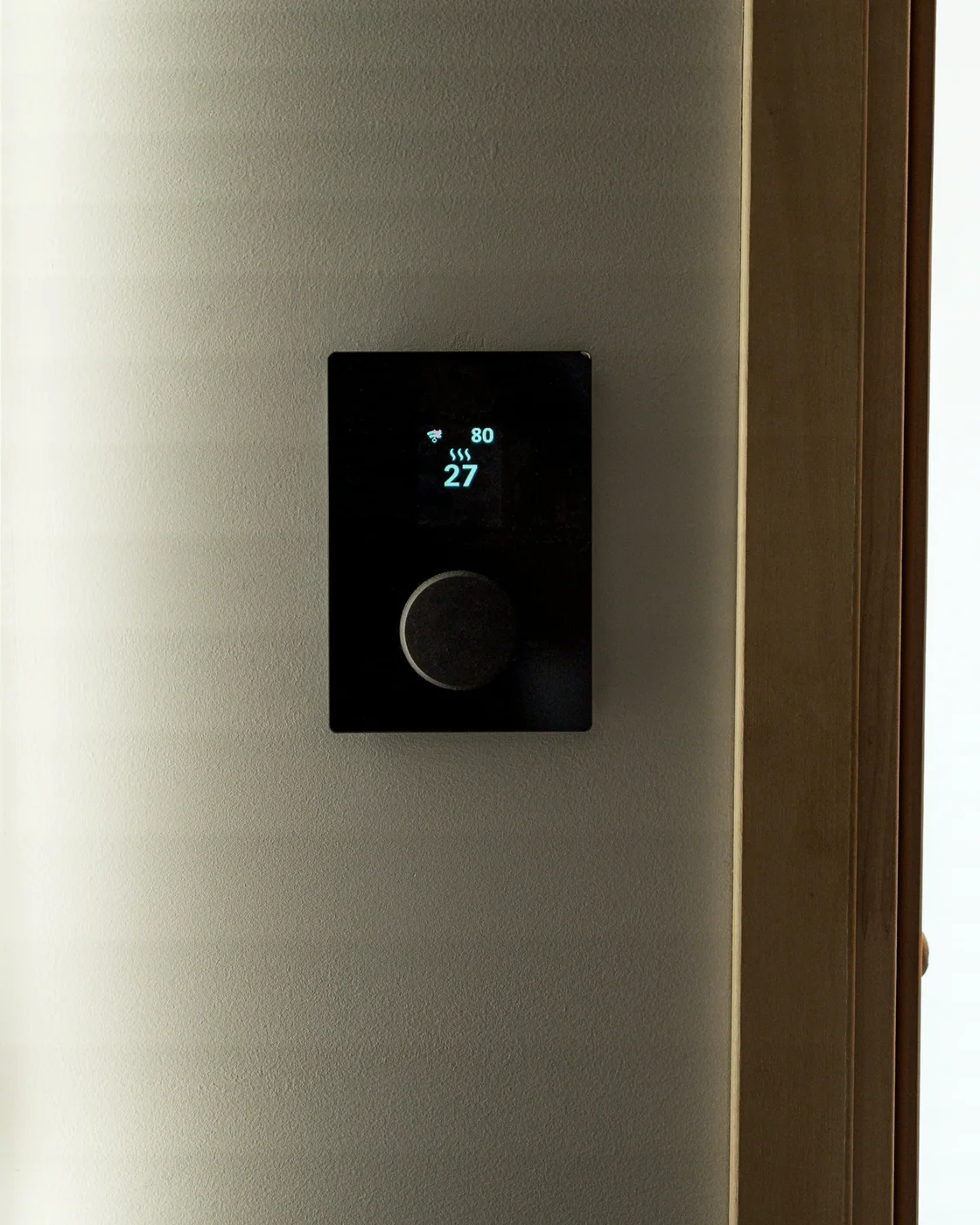 A discreet black wall control installed beside a window in a refined interior