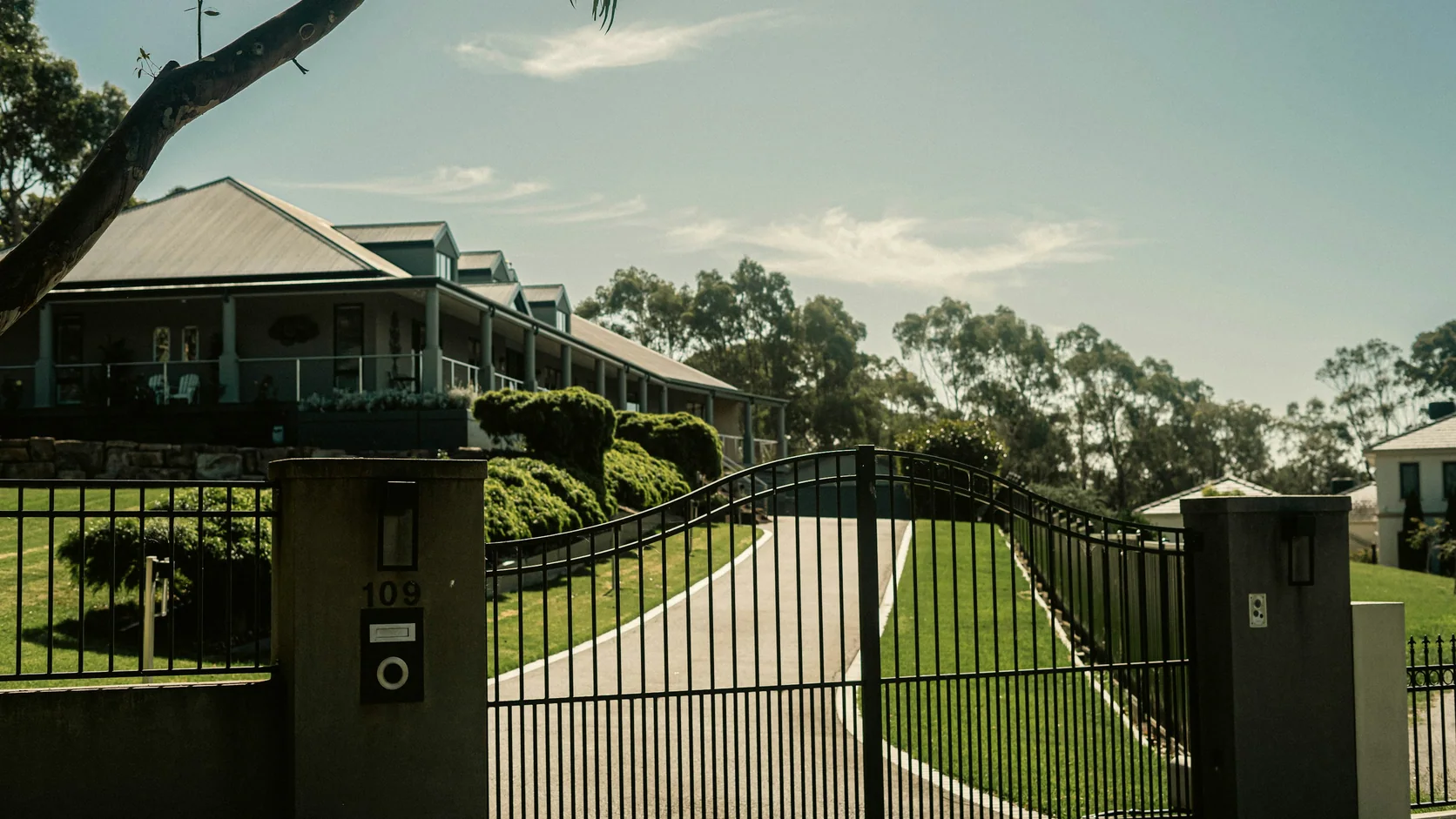 A gated private driveway with an entry intercom and residence beyond